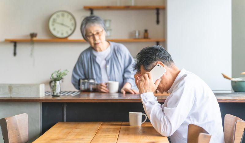 悩んで電話してる男性